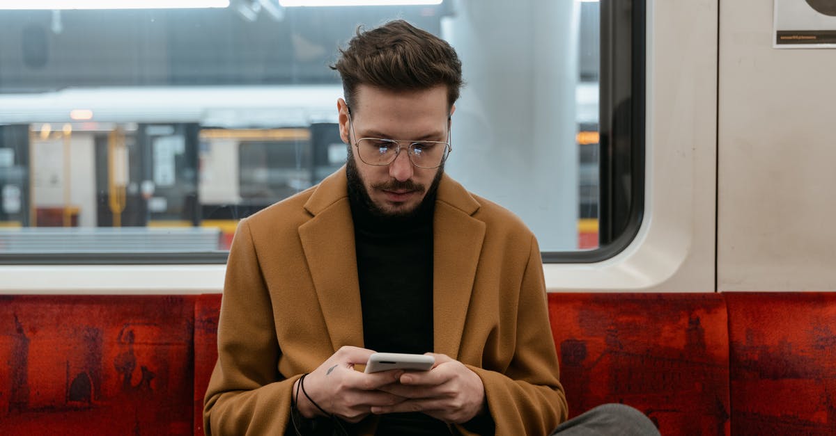 How to get off a London bus when sitting on the top deck? - Man in Brown Coat Sitting on Red Seat while Texting