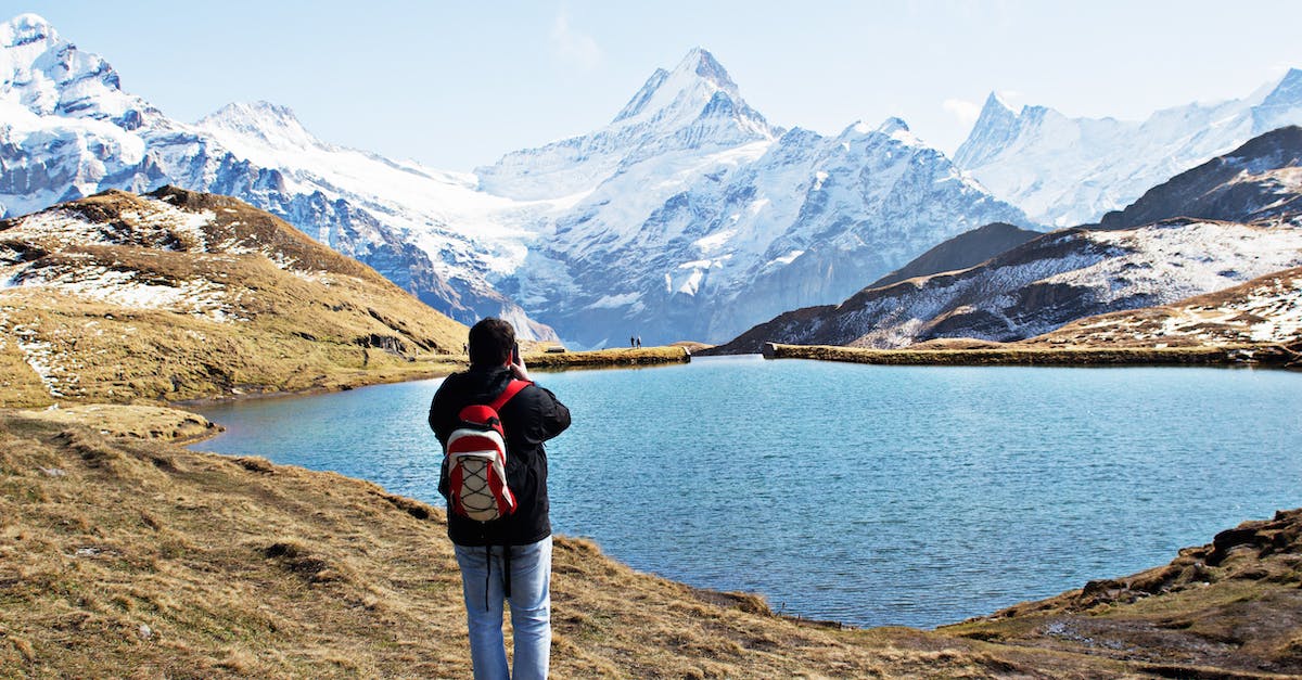 How to go about backpacking to Europe for the first time [closed] - Standing Man Wearing White and Red Backpack in Front of Calm Body of Water