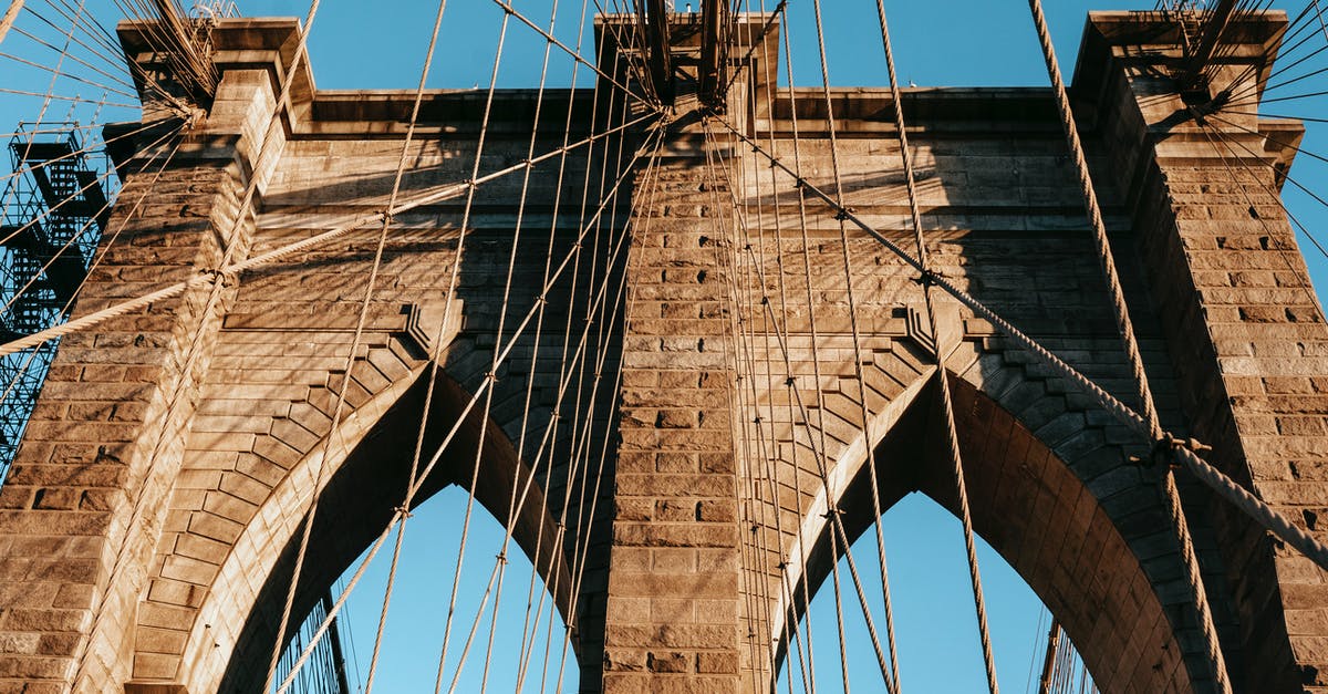 How to go cheap way (train/bus/flight) from New York city to Oklahoma city (Stillwater)? [closed] - Low angle of famous Brooklyn brick arches with ropes on top of bridge in metropolis