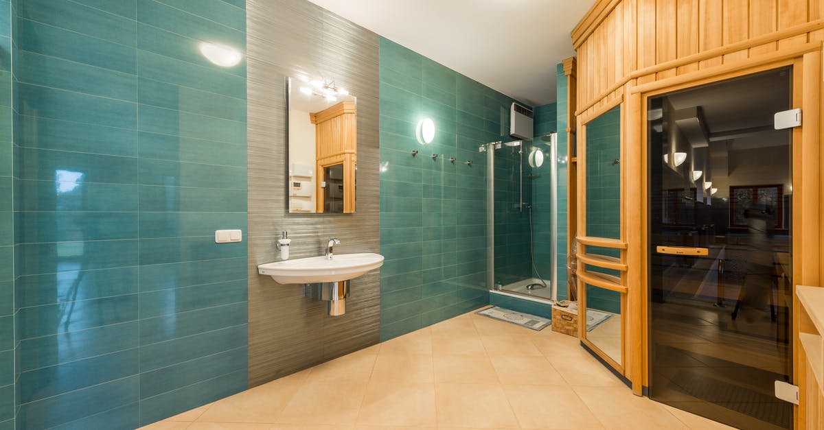How to interpret austrian sauna timetables - Interior of light shower room with glass cabin and sink and wooden entrance to sauna room with glass doorway How to interpret austrian sauna timetables - Interior of light shower room with glass cabin and sink and wooden entrance to sauna room with glass doorway