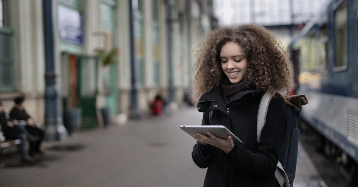 How to keep electronics warm in cold countries? - Cheerful young lady browsing tablet while waiting for train on platform How to keep electronics warm in cold countries? - Cheerful young lady browsing tablet while waiting for train on platform