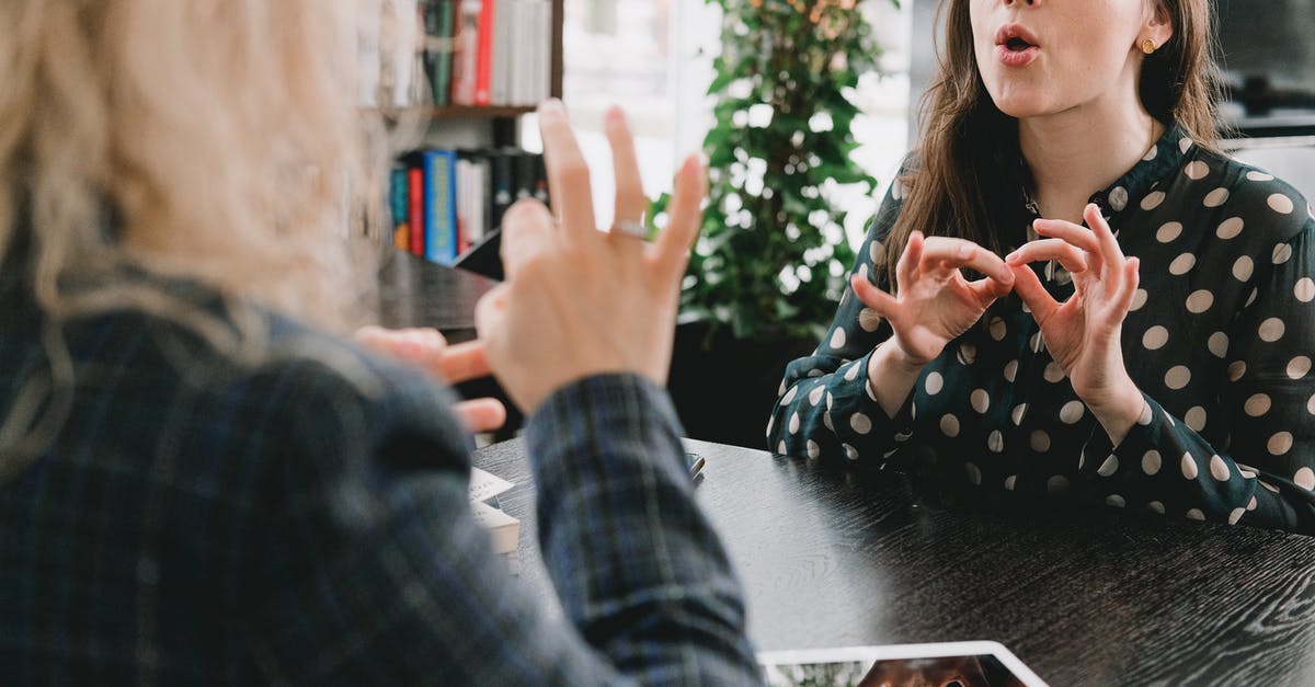 How to learn the language for a stay in Ukraine? [duplicate] - Young female friends communicating using sign language in library
