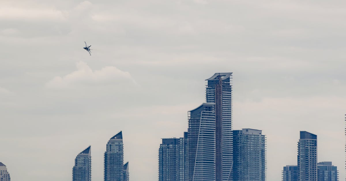 How to make complex multi-leg flight reservations? - Military airplane flying above modern skyscrapers in city How to make complex multi-leg flight reservations? - Military airplane flying above modern skyscrapers in city