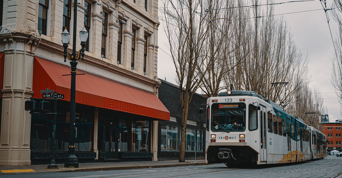 How to manage a longer transit location in a cheaper way - Modern tramway moving on railway near old houses along leafless trees in city How to manage a longer transit location in a cheaper way - Modern tramway moving on railway near old houses along leafless trees in city