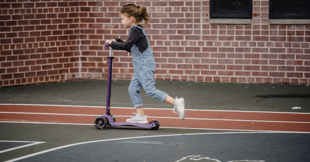 How to move children in a Las Vegas casino? - Side view of excited preschool girl in casual outfit riding scooter on asphalt sports ground How to move children in a Las Vegas casino? - Side view of excited preschool girl in casual outfit riding scooter on asphalt sports ground