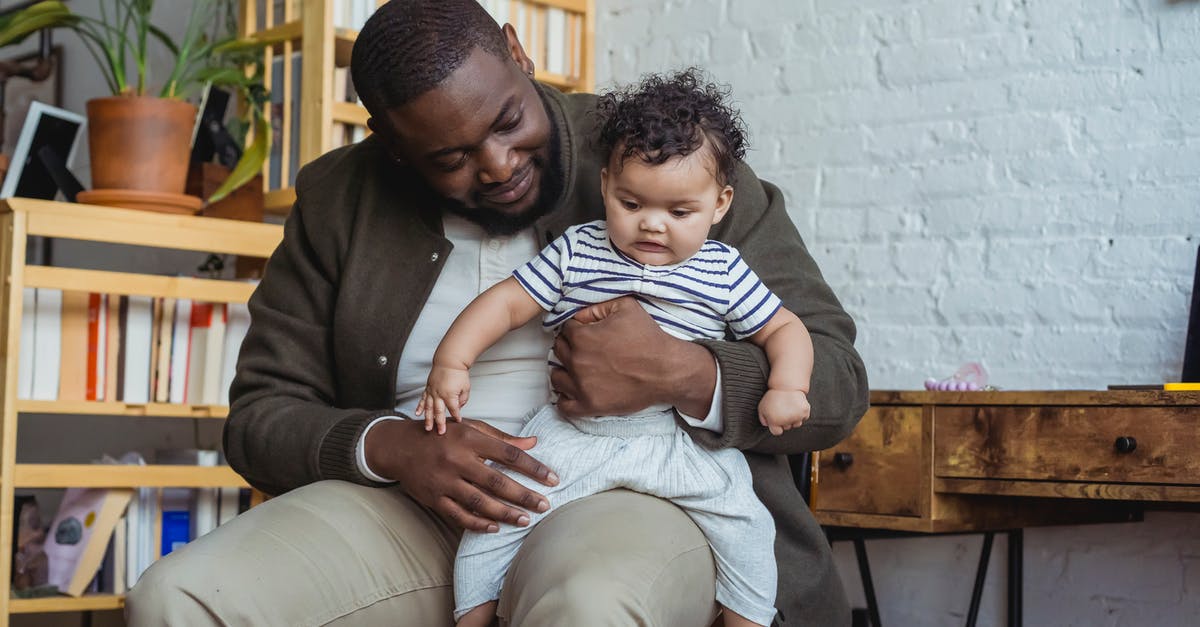 How to pass the time on a six-hour layover with small children (in Frankfurt)? [closed] - Caring African American man hugging and holding on knees adorable little baby while spending free time home with family