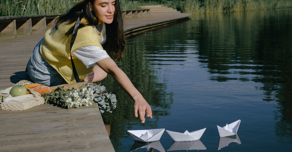 How to reach the clearest lake in the world? - Woman on Wooden Dock Reaching the Floating Paper Boats on Lake How to reach the clearest lake in the world? - Woman on Wooden Dock Reaching the Floating Paper Boats on Lake