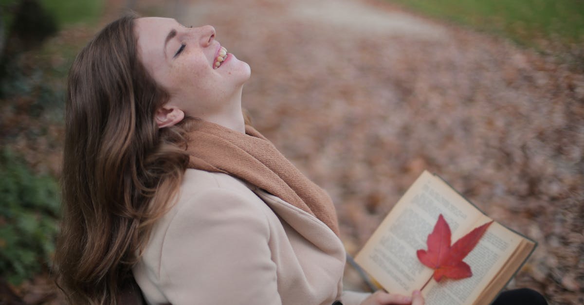 How to read female clothing labels in Poland? [closed] - Cheerful young woman with red leaf enjoying life and weather while reading book in autumn park