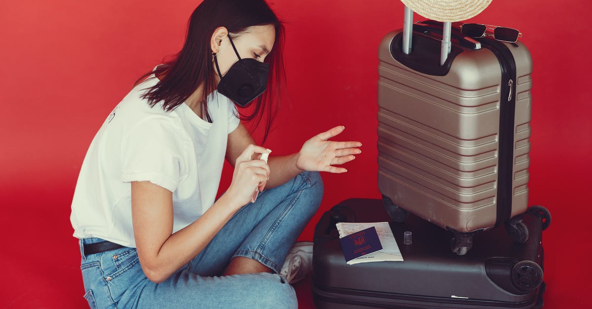 How to review a tour operator after medical emergency? - Side view of young woman in casual clothes and medical mask sitting near luggage with passport and tickets while disinfecting hands on red background How to review a tour operator after medical emergency? - Side view of young woman in casual clothes and medical mask sitting near luggage with passport and tickets while disinfecting hands on red background