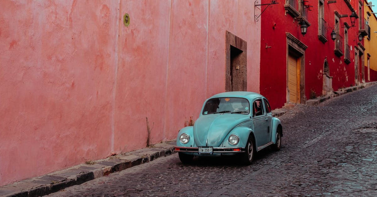 How to search for a rental car along a segment of I95? - Turquoise Buggy Moving Along Street with Pink and Red Buildings