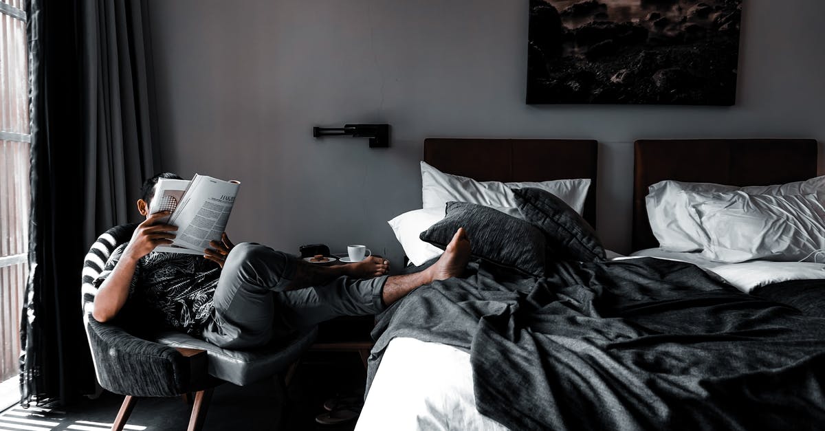 How to stay comfortable in beds found in American hotels? - Man Sitting on Chair Reading Book How to stay comfortable in beds found in American hotels? - Man Sitting on Chair Reading Book