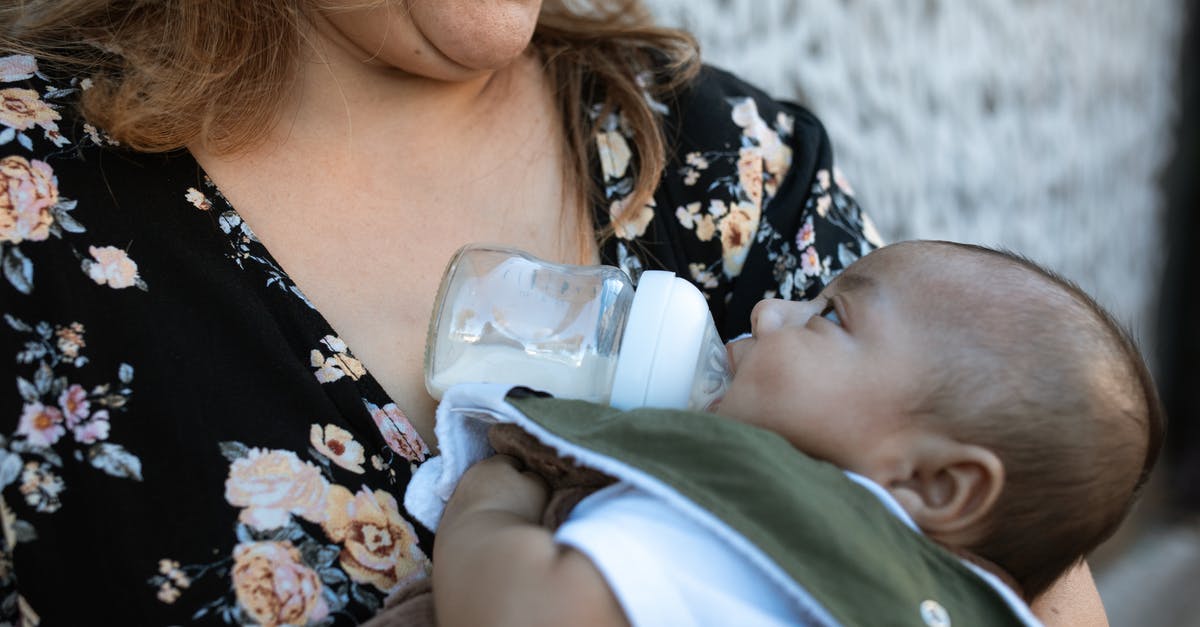 How to sterilize infant feeding bottles while traveling? - A Woman in Floral Shirt Carrying a Baby while Drinking Milk How to sterilize infant feeding bottles while traveling? - A Woman in Floral Shirt Carrying a Baby while Drinking Milk