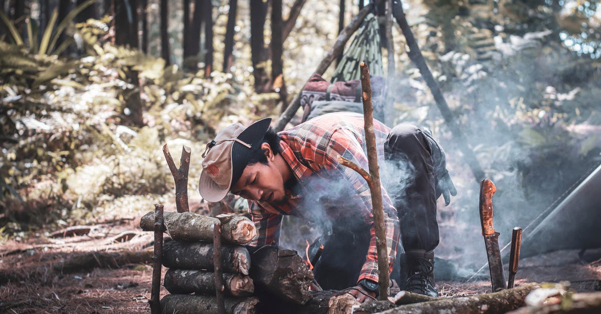 How to survive a timeshare promotional trip? - Ethnic man preparing bonfire in forest during expedition How to survive a timeshare promotional trip? - Ethnic man preparing bonfire in forest during expedition