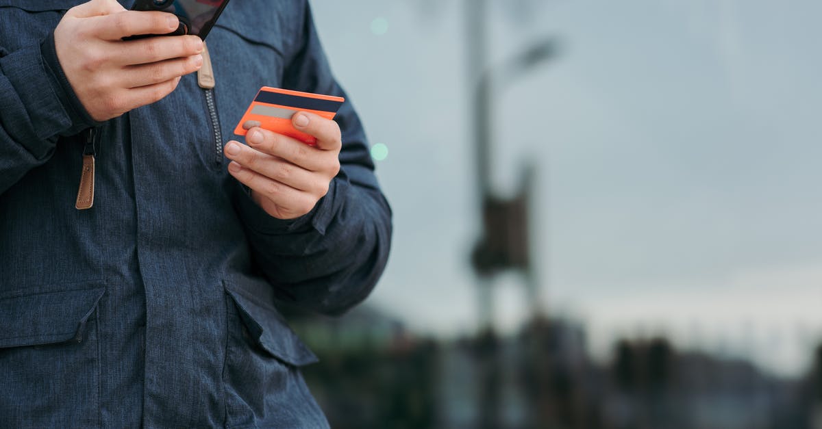 How to take money to Iran? - Male taking photo of credit card on smartphone on street in daytime How to take money to Iran? - Male taking photo of credit card on smartphone on street in daytime