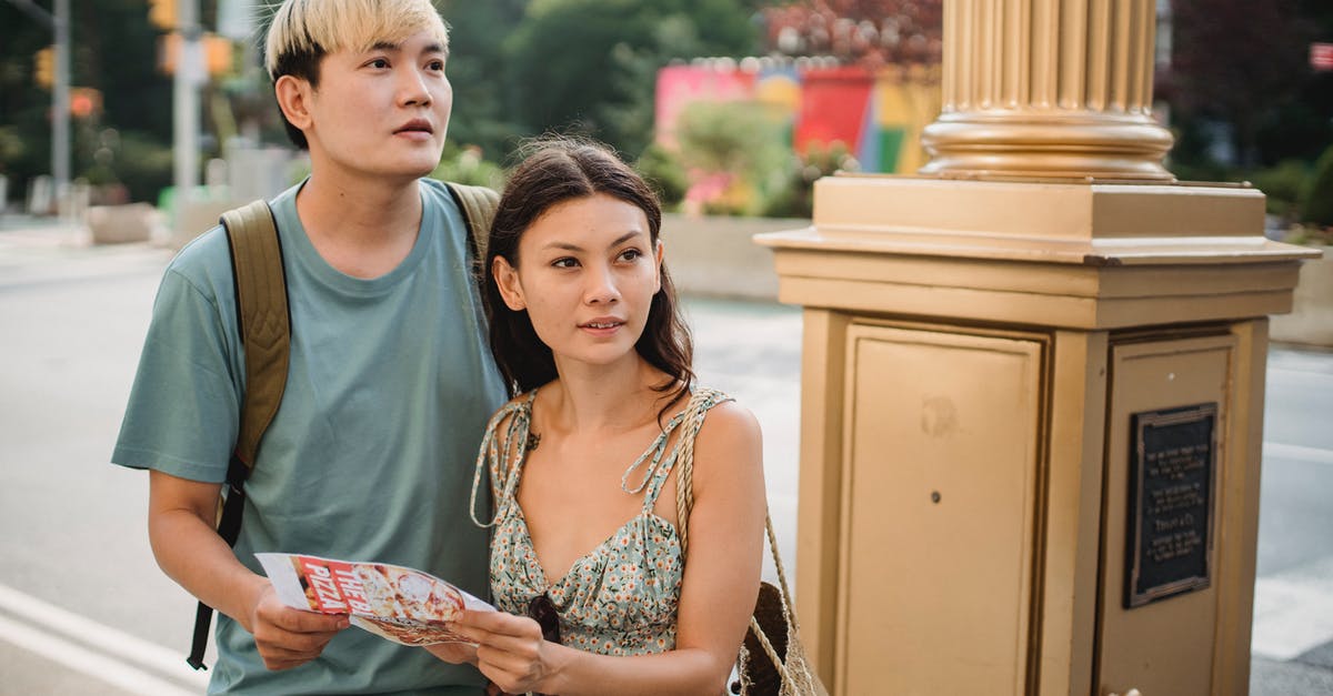 How to visit attractions in Tasmania without a car? - Cheerful Asian couple with map navigating in city How to visit attractions in Tasmania without a car? - Cheerful Asian couple with map navigating in city