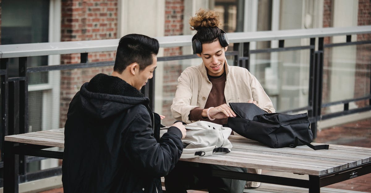 How useful or necessary is a pacsafe for your backpack? - Cheerful young multiethnic friends sitting at table and taking out necessary stuff from backpacks preparing to work together How useful or necessary is a pacsafe for your backpack? - Cheerful young multiethnic friends sitting at table and taking out necessary stuff from backpacks preparing to work together
