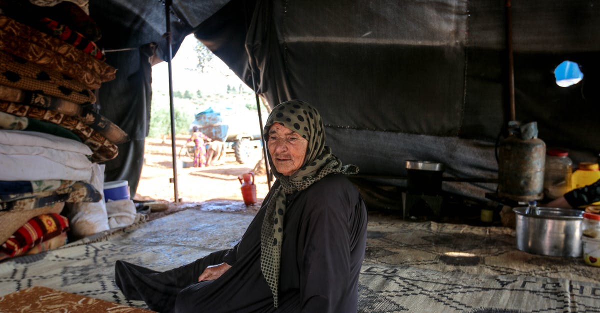 I am interested in visiting a refugee camp. What would be a good place to do so in Europe? [closed] - Full body of senior female in headscarf sitting on plaid in shabby tent with roof in poor refugee camp in countryside