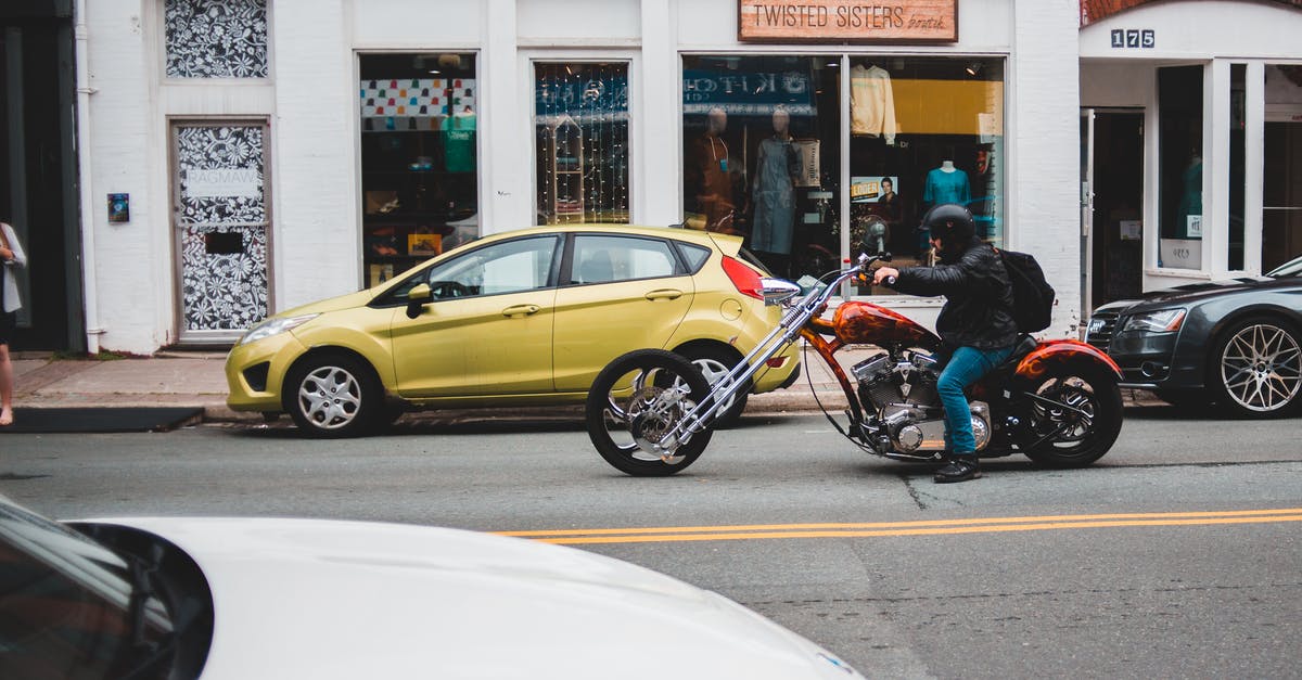 I have a cool suitcase. Might be tricky to ride a motorbike. Looking for a strap allowing to carrying it as a backpack? - Man riding chopper on asphalt road
