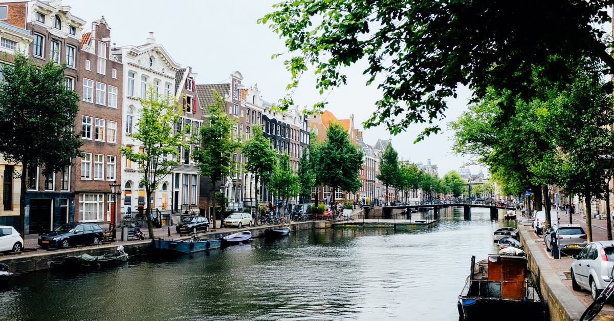 I have a netherlands visa, can my port of entry be Madrid? [duplicate] - Exterior of small Dutch houses situated on canal shore in sunny spring Amsterdam