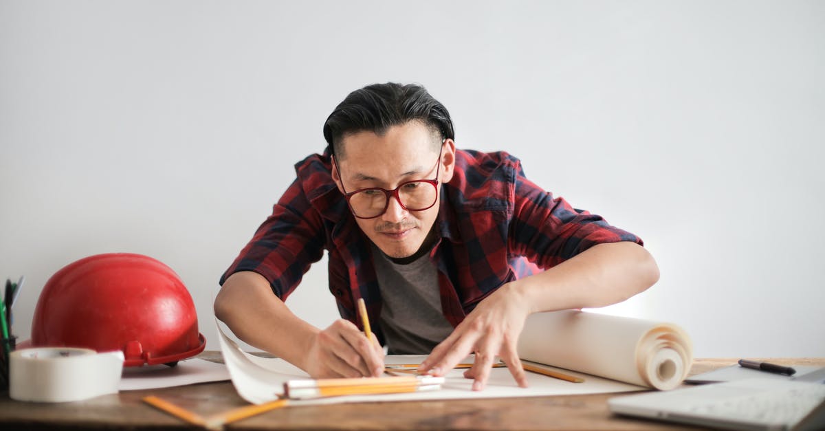 I live in New Zealand and have a job offer from an Australian company. It's a remote position. Can I stay in New Zealand and work? [closed] - Inspired young male engineer in glasses drawing draft on paper bending over table against white wall