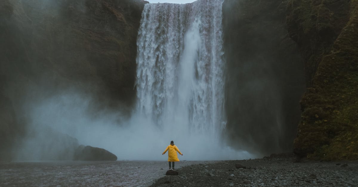 Iceland - Visiting fjords from Reykjavík in 1 day - Person in Yellow Clothes by the Waterfall Iceland - Visiting fjords from Reykjavík in 1 day - Person in Yellow Clothes by the Waterfall