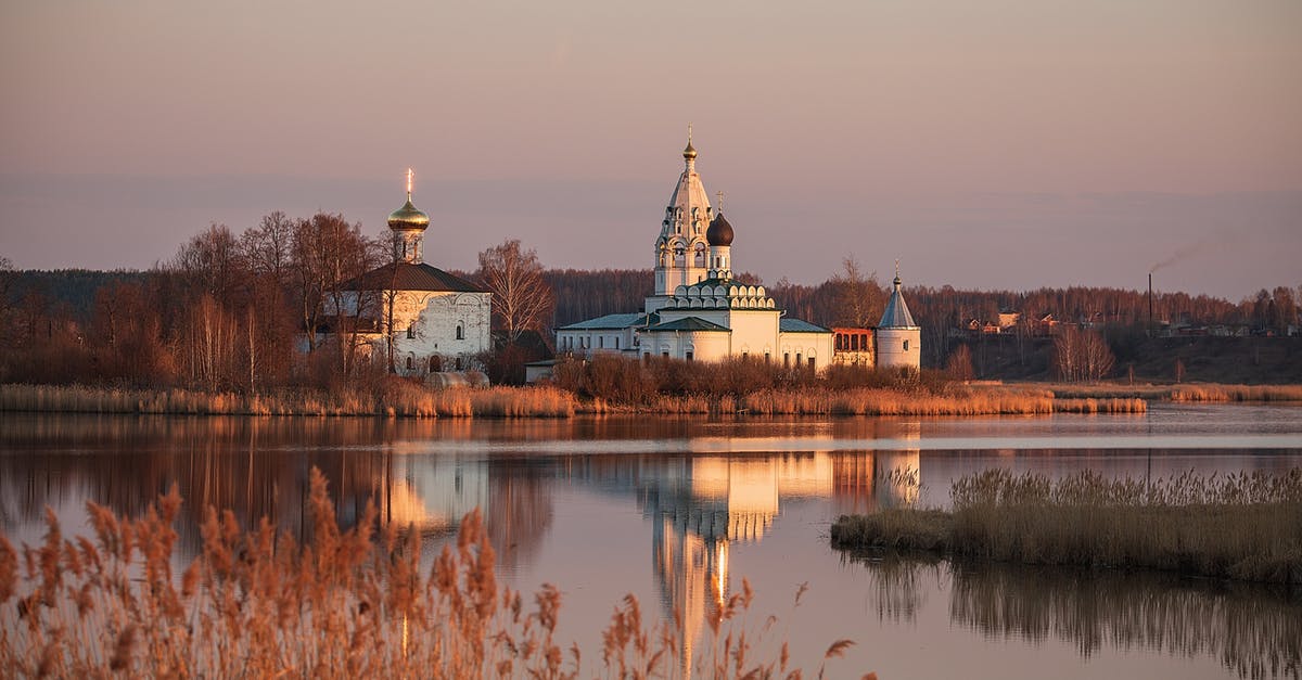 Identify waterside building / skyline - Scenery view of church with domes and withered trees located on shore of calm lake against cloudless sky in sunset Identify waterside building / skyline - Scenery view of church with domes and withered trees located on shore of calm lake against cloudless sky in sunset