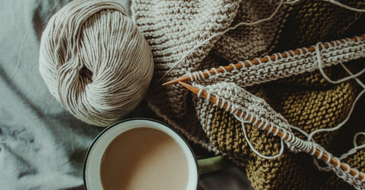 If arriving in Estonia in winter from a warm climate, is it easy to find good secondhand winter clothes? - From above of cup of hot coffee placed on bed with handmade knitted plaid with needles and wool yarn If arriving in Estonia in winter from a warm climate, is it easy to find good secondhand winter clothes? - From above of cup of hot coffee placed on bed with handmade knitted plaid with needles and wool yarn