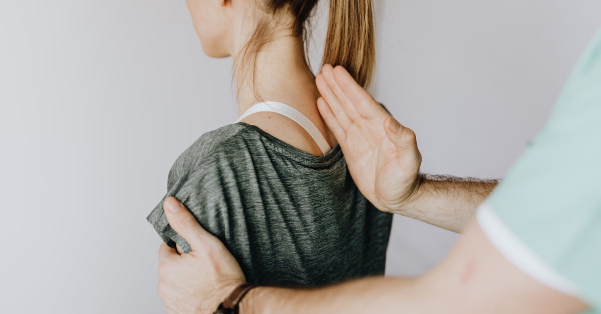 If I have an outstanding medical bill in America, can I go back there? [duplicate] - Back view of crop unrecognizable osteopath in uniform and wristwatch checking up back of slim female patient in casual wear on white background