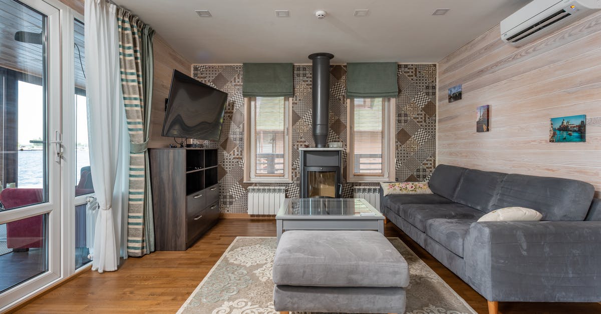 If I live in my home country, should I apply for a UK visa with my home country passport or can I apply with my other country passport? [closed] - Modern design of country house with light wooden walls and carpet with ornament on parquet and dark gray furniture and curtains on wide balcony door and narrow windows