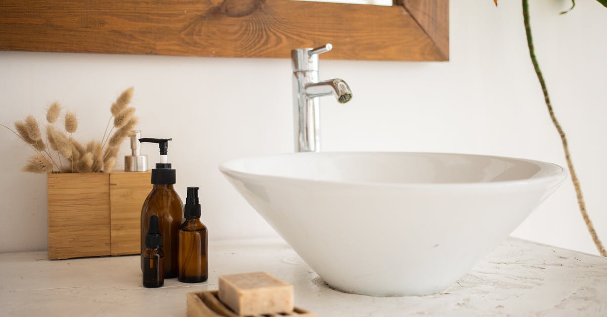 Importing wooden trinkets into New Zealand and Australia - Interior of bathroom table with soap and cosmetic oil placed near white sink and faucet under mirror in wooden frame in modern apartment Importing wooden trinkets into New Zealand and Australia - Interior of bathroom table with soap and cosmetic oil placed near white sink and faucet under mirror in wooden frame in modern apartment