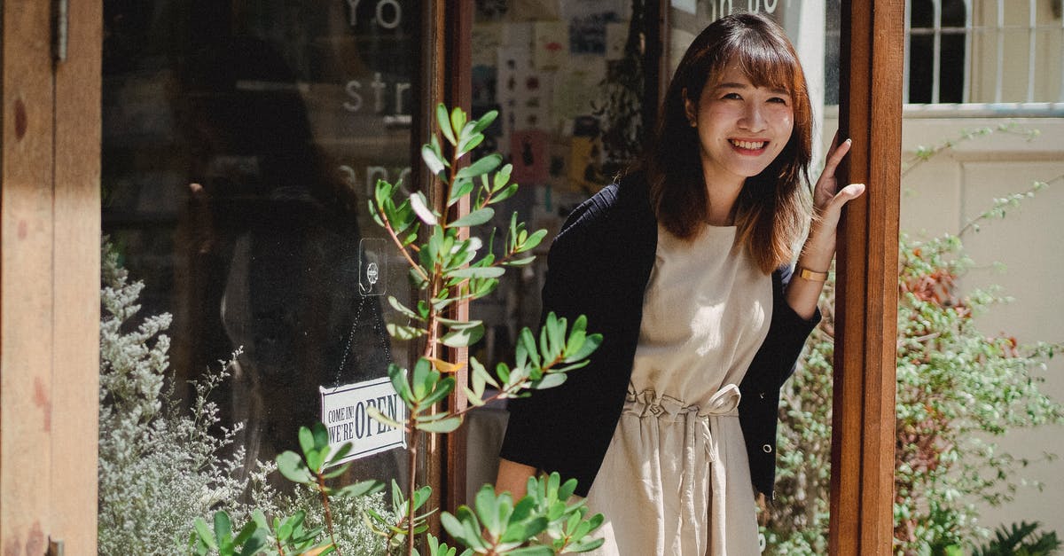 In Costa Rica - Invite Strangers to Dinner? - Smiling Asian woman in apron standing on store doorway In Costa Rica - Invite Strangers to Dinner? - Smiling Asian woman in apron standing on store doorway