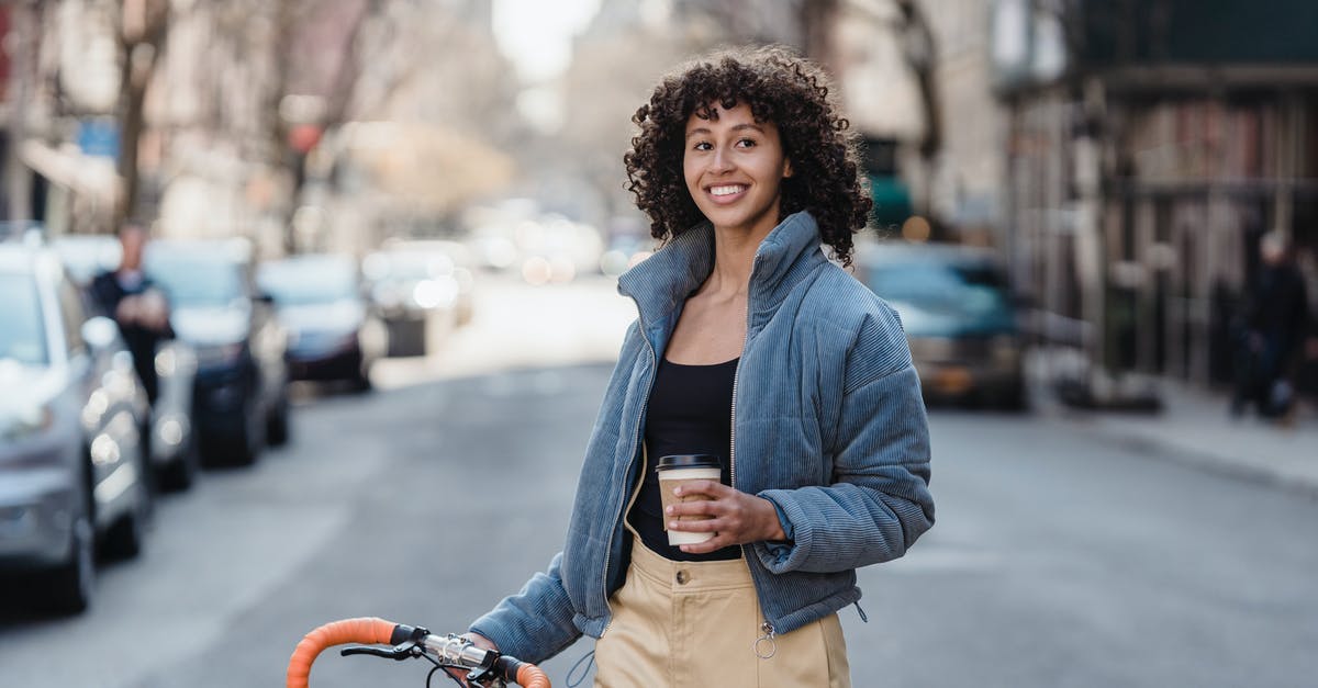 In Mongolia, what kind of vehicle is a jeep? - Smiling ethnic woman with coffee and bike on urban road In Mongolia, what kind of vehicle is a jeep? - Smiling ethnic woman with coffee and bike on urban road