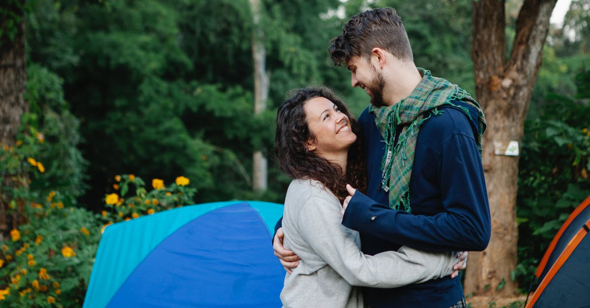 In the high season in Ontario, is it possible to camp on campsites without early pre-reservations? - Smiling happy couple near blue tent in forest In the high season in Ontario, is it possible to camp on campsites without early pre-reservations? - Smiling happy couple near blue tent in forest