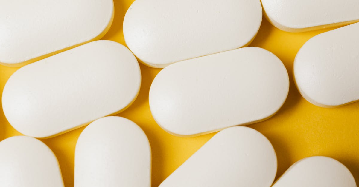 In transit with controlled medication - From above closeup of white ellipse shaped medical pills placed on bright yellow surface In transit with controlled medication - From above closeup of white ellipse shaped medical pills placed on bright yellow surface