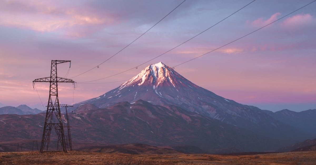 Inclement weather at destination airport during layover in a foreign country - High voltage power lines against mountains in sunset