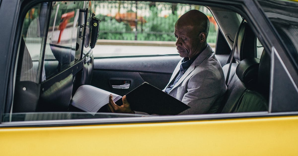 Independent contracting around the world - Pensive black entrepreneur examining important report in car Independent contracting around the world - Pensive black entrepreneur examining important report in car