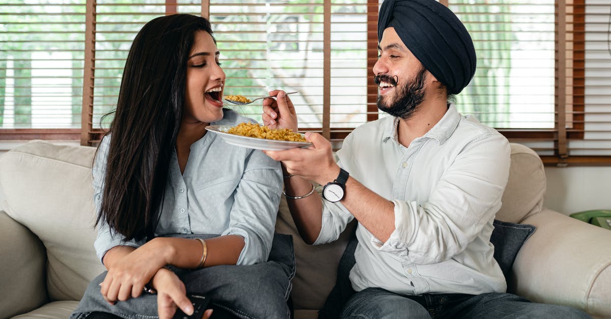 Indian National, Living in New Zealand looking to go to Europe [closed] - Delighted ethnic couple having meal on sofa in living room