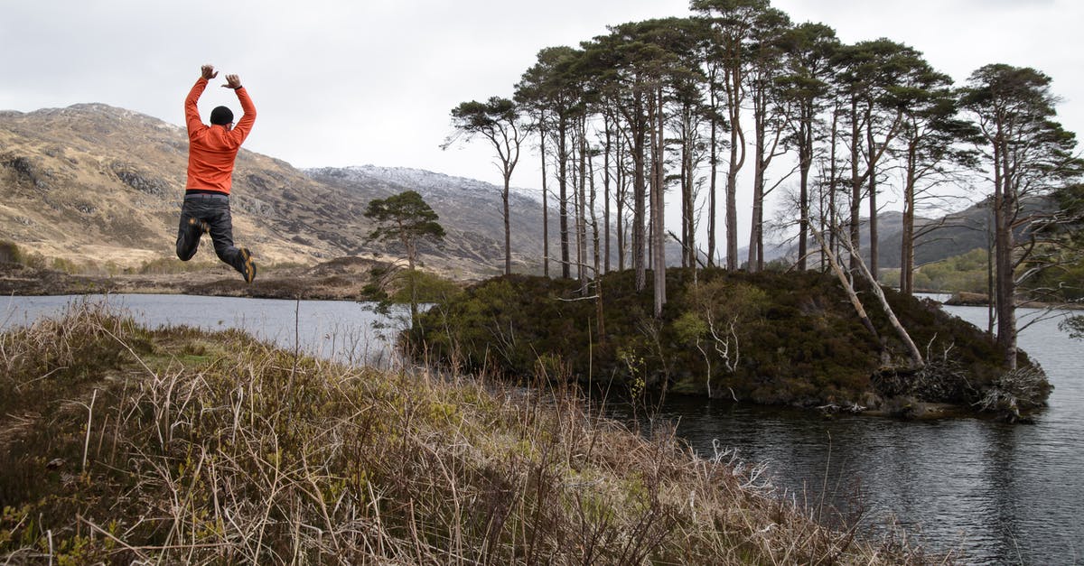 Indian passport traveling to Scotland - Man in Orange Long-sleeved Shirt Jumping on Lake Near Tall Trees at Daytime Indian passport traveling to Scotland - Man in Orange Long-sleeved Shirt Jumping on Lake Near Tall Trees at Daytime