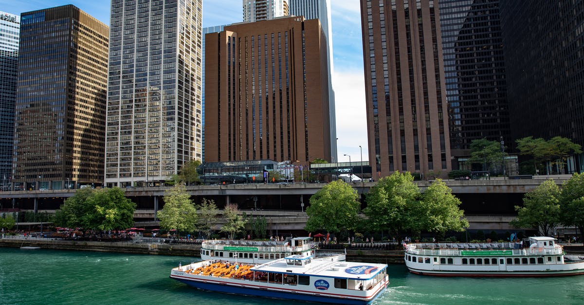 Inner tubing down rivers in the United States - White and Blue Boat on Body of Water Near High Rise Buildings Inner tubing down rivers in the United States - White and Blue Boat on Body of Water Near High Rise Buildings
