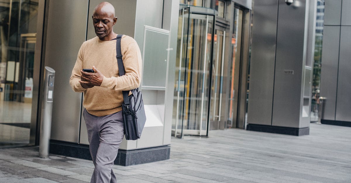 Interlining: How is responsibility distributed in case of a missed connection? [duplicate] - Mature bald black man in elegant clothes and with case bag texting on smartphone while walking down street
