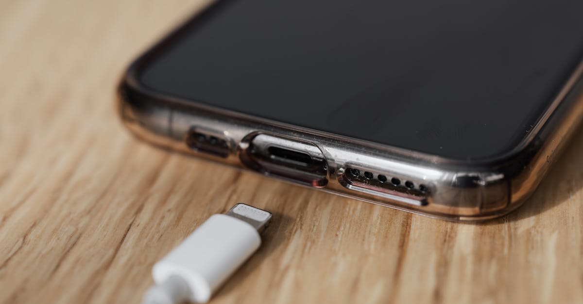 International SMS Charges - Modern cellphone in transparent cover with closeup of charging input and mobile phone white charger cable usb connector on wooden table International SMS Charges - Modern cellphone in transparent cover with closeup of charging input and mobile phone white charger cable usb connector on wooden table