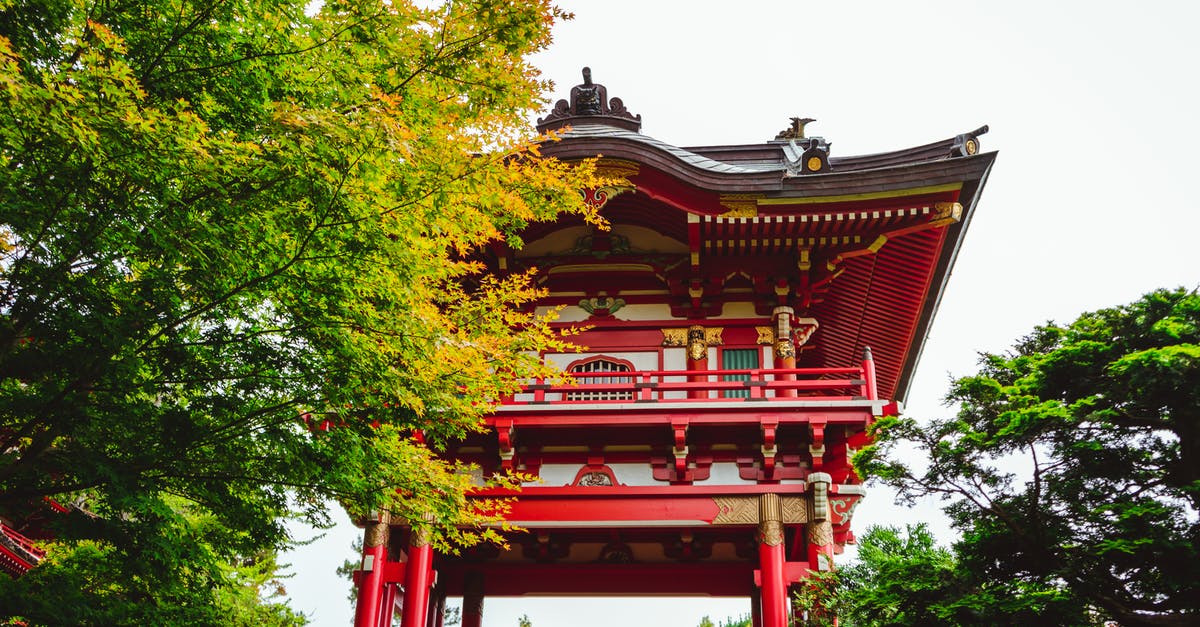 International travel of minor with dual Japanese and US citizenship - Low angle exterior of traditional aged red Asian temple surrounded by lush green trees in Japanese Tea Garden located in San Francisco on sunny day International travel of minor with dual Japanese and US citizenship - Low angle exterior of traditional aged red Asian temple surrounded by lush green trees in Japanese Tea Garden located in San Francisco on sunny day