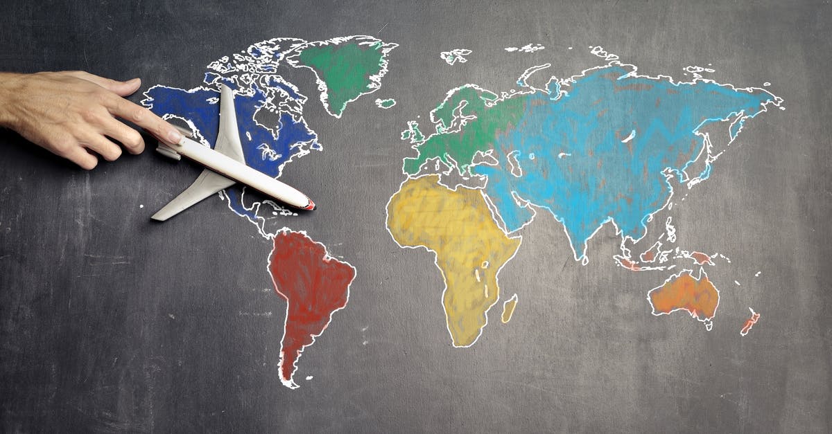 International travel with connecting flights with different airlines - Top view of crop anonymous person holding toy airplane on colorful world map drawn on chalkboard