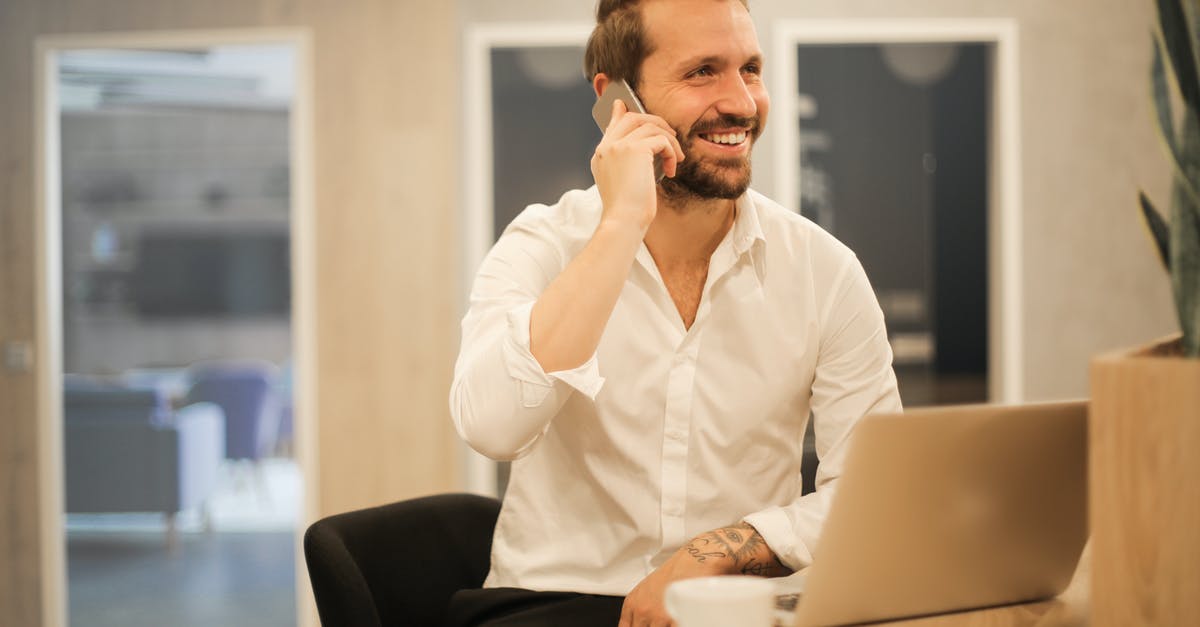 Internet access using mobile phone in Argentina - Smiling formal male with laptop chatting via phone Internet access using mobile phone in Argentina - Smiling formal male with laptop chatting via phone