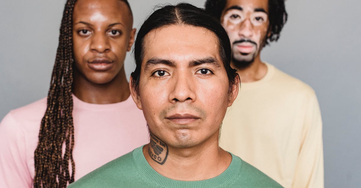 Is American Express widely accepted in UK? - Expressive multiethnic male friends in trendy wear standing in studio and looking at camera Is American Express widely accepted in UK? - Expressive multiethnic male friends in trendy wear standing in studio and looking at camera