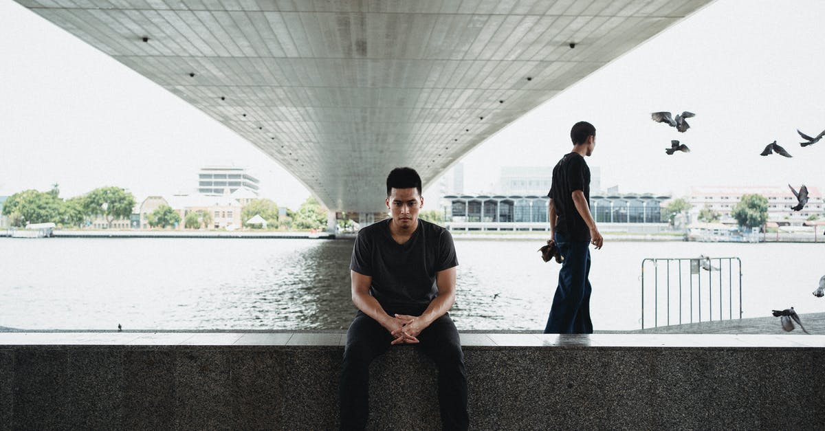 Is appearance important at the border? - Asian man sitting on embankment under bridge Is appearance important at the border? - Asian man sitting on embankment under bridge