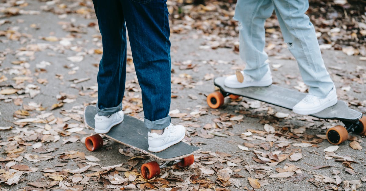 Is Cambridge Park and Ride free without taking the bus? - Crop legs of anonymous people in jeans and sneakers riding skateboards on asphalt walkway in park in autumn day
