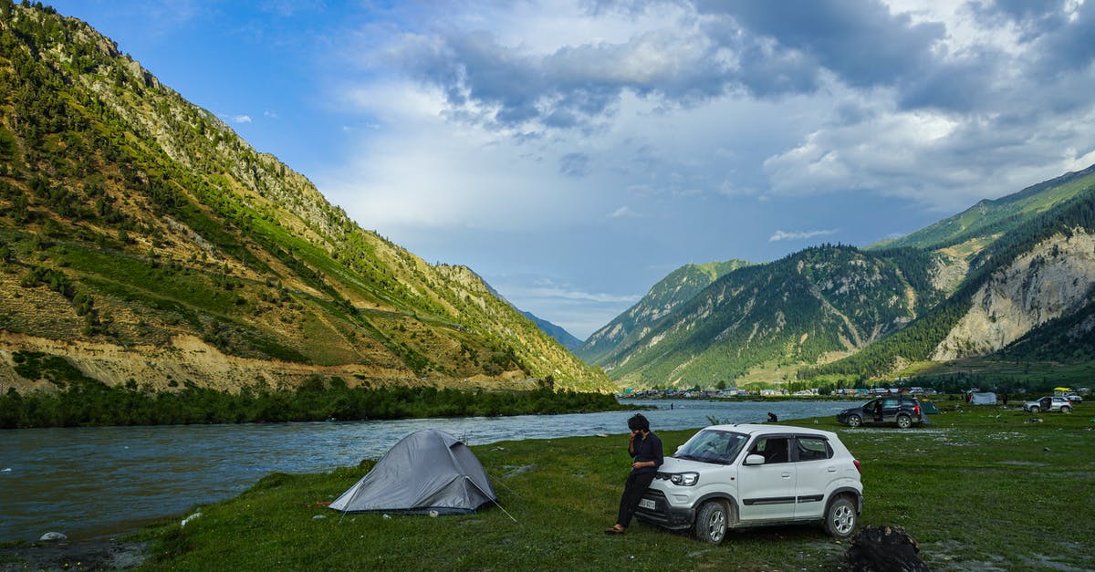 Is camping still permitted in Zzyzx? - Man in Black Shirt Sitting on Ground Beside White Suv