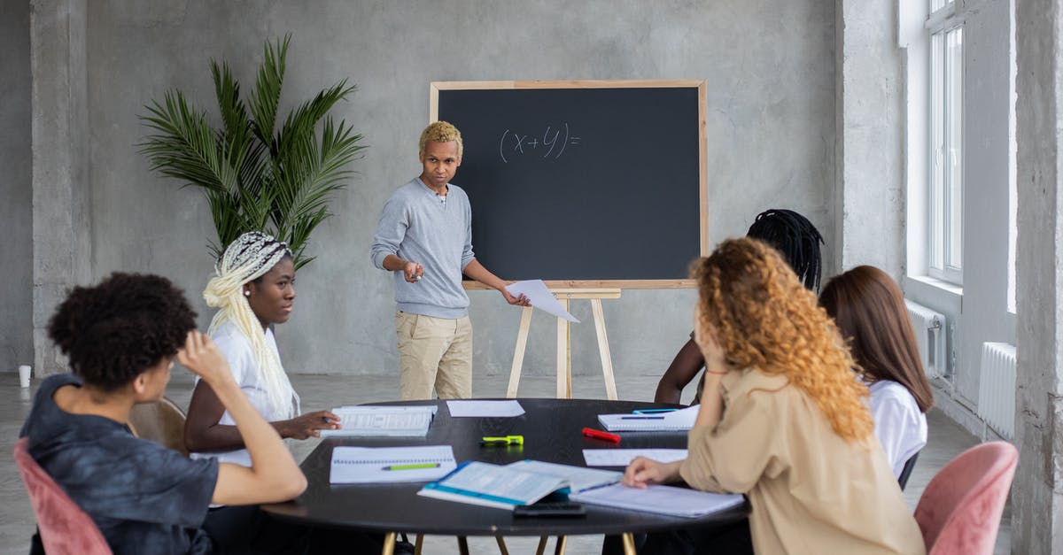 Is it better to ask a question in English or Japanese if you are expecting a reply in English? - African American student explaining mathematic equation to diverse classmates while doing homework together in spacious room
