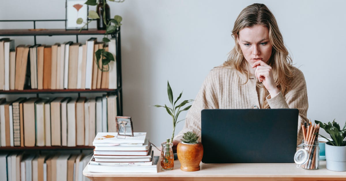 Is it cheaper to book a hotel online or at the desk? [closed] - Serious female surfing internet on netbook while sitting at table near wall in light room with collection of books on shelves